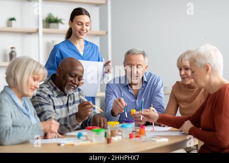 Glückliche ältere Männer und Frauen, die gemeinsam Kunsthandwerk machen Stockfoto