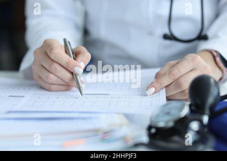 Arzt Kardiologe, der das Kardiogramm des Patienten in der klinischen Nahaufnahme auf Papier untersucht Stockfoto