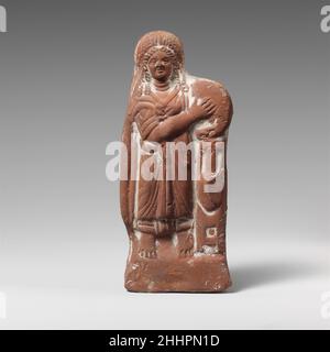 Terrakotta-Statuette einer Frau mit Tympanon ca. 2nd. Jahrhundert A.D. Roman, ägyptisch verschleiert, Tympanon in beiden Händen haltend und mit linkem Arm auf hohe Vase lehnend. Terrakotta-Statuette einer Frau mit Tympanon 245508 Stockfoto