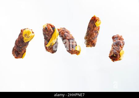 Schwebendes mici oder mitititei (traditionelle rumänische Küche) mit Senf auf weißem Hintergrund Stockfoto