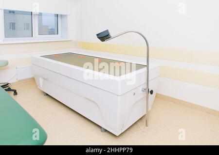 Massageliege im Klinikraum. Rehabilitationszentrum des Krankenhauses. Moderne medizinische Geräte, Konzept der präventiven Medizin. Modernes Krankenhauslabor Stockfoto