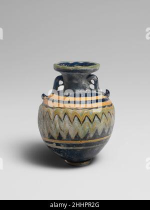 Glas Aryballos (Parfümflasche) Ende 6th–5th Jahrhundert v. Chr. Griechisch, östliches Mittelmeer Durchscheinendes Kobaltblau, mit gleichen farbigen Griffen; Trails in undurchsichtigem Türkisblau und undurchsichtigem Gelb. Breite nach innen abfallende ovale Randscheibe mit strahlenden Werkzeugmarkierungen auf der Oberseite; zylindrischer Hals; fast horizontale Schulter; fast kugelförmiger Körper; konvex, Leicht spitz zulaufende Unterseite; zwei Ringgriffe mit geklopften Schwänzen, über der Traildekoration angebracht, erstrecken sich von der Schulter bis zum Hals.Eine türkisblaue Spur wird am äußeren Rand der Randscheibe angebracht; eine breite gelbe Spur wird am Oberkörper aufgetragen und spiralförmig nach unten gewickelt, AT Stockfoto