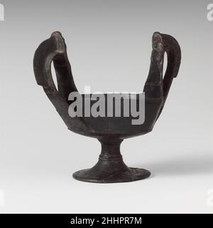 Terrakotta-Kantharos (Trinkbecher mit hohen Griffen) 6th. Jahrhundert v. Chr. Etrusker an jedem Griff, eine Figur im ReliefDiese Form von Kantharos ist in Form mit dem Kyathos verwandt. Das Kantharos ist in der attischen Töpferei durch 600 B.C. bekannt, und es kam, spezifisch mit dem weingott Dionysos verbunden zu werden.. Kantharos aus Terrakotta (Trinkbecher mit hohen Griffen) 246226 Stockfoto