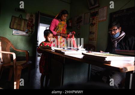 Die Schüler werden in eine ländliche Grundschule aufgenommen, und neue Schulbücher werden frei an die Schüler verteilt, die von der Regierung zur Verfügung gestellt werden. Nabin Nagar, Indien. Stockfoto