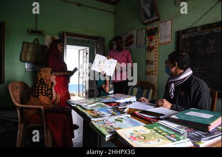 Die Schüler werden in eine ländliche Grundschule aufgenommen, und neue Schulbücher werden frei an die Schüler verteilt, die von der Regierung zur Verfügung gestellt werden. Nabin Nagar, Indien. Stockfoto