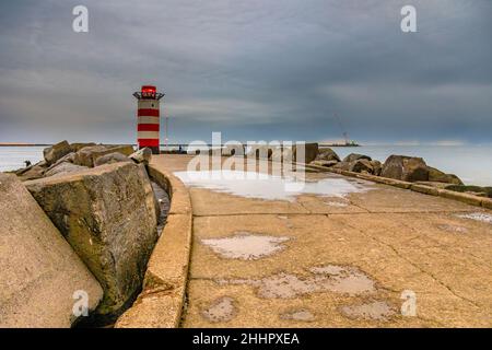 Betonsteg in der Nähe von IJmuiden mit Angler Fischer an einem bewölkten Nachmittag. Provinz Nordholland, Niederlande Stockfoto