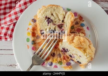 Exquisiter hausgemachter Cupcake oder Muffin mit Heidelbeeren und Brombeeren, die auf einem weißen Teller auf einem rustikalen Tisch halbiert werden. Hausgemachte Speisen, natürliche Lebensmittel. Stockfoto