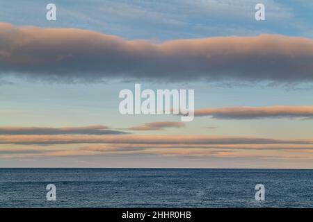 CULLEN, MORAY, SCHOTTLAND - 23. JANUAR 2022: Dies sind die Wolkenlinien, die am Sonntag, dem 23. Januar, in Cullen, Moray, Schottland die letzten Sonnenstrahlen bekommen Stockfoto