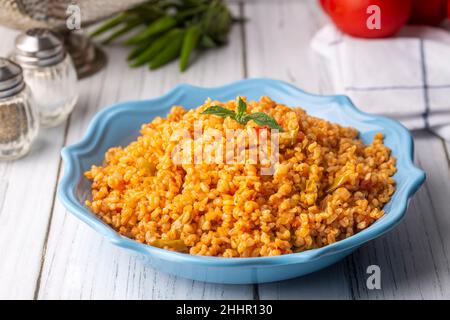 Traditioneller türkischer Bulgur-Pilaf mit Tomatensoße auf dem Teller (türkischer Name; Meyhane pilavi) Stockfoto