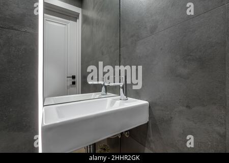Wasserhahn aus Metall mit Waschbecken und Wasserhahn zum Einschalten und Regeln von kaltem oder heißem Wasser im teuren Badezimmer. Stockfoto