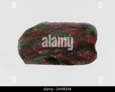 Glasmosaik-Inlay-Fragment Ende des 1st. Jahrhunderts v. Chr.–Anfang des 1st. Jahrhunderts n. Chr. römisch Transparent blaugrün und opak ziegelrot.flache, rechteckige Plakette mit zwei langen geraden Seiten und abgerundeten Ecken; unregelmäßige Werkzeugeinzüge auf der Unterseite.Marmormosaik-Muster in blaugrünem Boden mit mehreren roten Streifen.abgebrockte Kanten; polierte Oberseite; Lochfraß von Oberflächenblasen; Abstumpfen und etwas Lochfraß auf der Unterseite; schillernde Verwitterung an den meisten Kanten, aber Teil einer langen Seite flach geschliffen. Glasmosaik-Inlay-Fragment. Römisch. Ende des 1st. Jahrhunderts v. Chr.–Anfang 1st Stockfoto