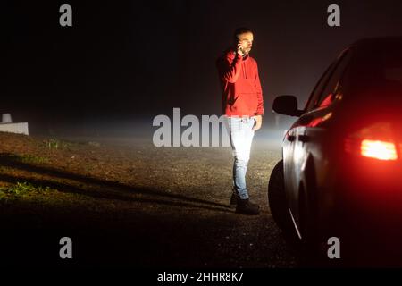 Mann, der die Versicherungsgesellschaft vor seinem heruntergekommenen Auto anruft Stockfoto