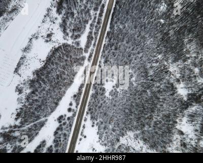 Drone-Bild mit hoher Neigung von oben nach unten auf der Straße Durch die Bäume und Wald in Bergkette mit bedeckt Weißer Schnee am Wintertag in der Nähe von Knjazevac Stockfoto