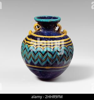 Glas Aryballos (Parfümflasche) Ende 6th–5th Jahrhundert v. Chr. Griechisch, östliches Mittelmeer Durchscheinendes Kobaltblau, mit Griffen in undurchsichtigem Gelb; Trails in undurchsichtigem Gelb und undurchsichtigem Türkisblau.breite nach innen abfallende Randscheibe; kurzer zylindrischer Hals; rechtwinklige Schulter; fast kugelförmiger Körper; konvex, Etwas spitz zulaufende Unterseite; zwei vertikale Ringgriffe mit geklopften Schwänzen, die über der Traildekoration angebracht sind, erstrecken sich von der Schulter bis zur Unterseite der Randscheibe.Türkisblauer Trail am äußeren Rand der Randscheibe angebracht; ein gelber Trail, unbemarkert, auf den Oberkörper aufgetragen und spiralförmig, zunächst horizontal gewickelt Stockfoto