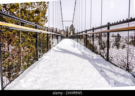 Schneebedeckte Hängebrücke über einem Wasserfall Stockfoto