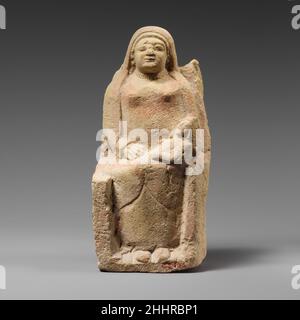Sitzende Kourotrophos aus Kalkstein Ende des 6th. Jahrhunderts v. Chr. zypriotische Statue der "stillenden Mutter" mit langem Schleier auf dem Thron mit hohen Rückenlehnen.die Frau nimmt einen Sitz mit teilweise gebrochenem Rücken und Armlehnen ein. Auf den Knien hält sie ein kleines Baby, das eine Kapuze trägt. Ihre rechte Hand ruht auf den Knien des Kindes. Sie trägt einen rot gefärbten Chiton auf ihrer Brust. Die Schimulation, die sich wie ein Schleier über ihren Kopf erstreckt, bedeckt die Arme und fällt über die Beine; der Rand ist rot gestrichen. Am rechten Handgelenk befindet sich ein Armband und an der Basis des Halses eine Halskette. Die Eigenschaften der runden Fläche sind grob. Es gibt Schlösser Stockfoto