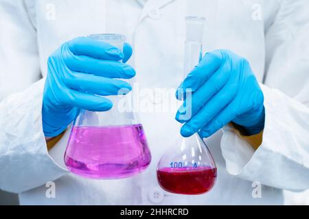 Wissenschaftler experimentieren mit hellen Lösungen in den Kolben im chemischen Labor. Forscher, die im modernen Zentrum für Mikrobiologie arbeiten. Stockfoto