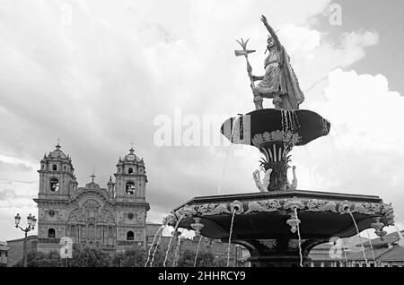 Monochrom-Bild der Inkas König Pachacutec Statue auf dem Brunnen mit der Kirche der Gesellschaft Jesu im Hintergrund, Cuzco, Peru Stockfoto