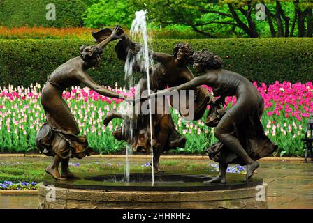 Tulpen blühen um drei tanzende Nymphen des Untermeyer Fountain im New Yorker Central Park Stockfoto