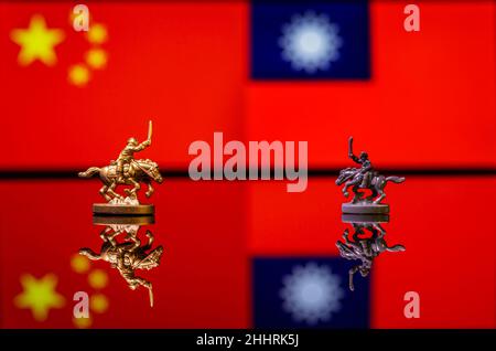 Konzeptuelles Bild des Krieges zwischen China und Taiwan mit Spielzeugsoldaten und Nationalflaggen auf einem reflektierenden Hintergrund Stockfoto