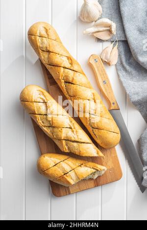 Gebratenes Baguette mit Knoblauchbutter. Knusprig geschnittenes Knoblauchbrot auf einem weißen Tisch. Stockfoto