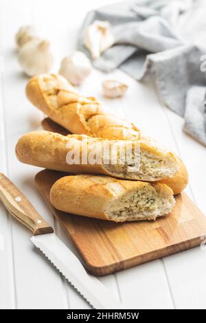 Gebratenes Baguette mit Knoblauchbutter. Knusprig geschnittenes Knoblauchbrot auf einem weißen Tisch. Stockfoto