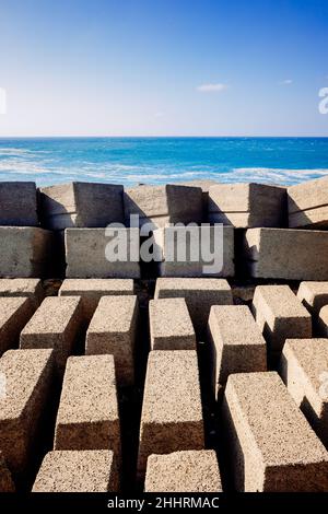 Steinblöcke an einem Damm eines Hafenmetzes an der Atlantikküste an einem sonnigen Tag. Stockfoto