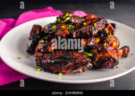 Chinese Five Spice Chicken Wings with Soy, Balsamic Reduction Glaze: Teller mit klebrigen Hähnchenwingettes und Drumettes, garniert mit Schnittlauch Stockfoto