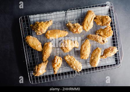 Ungekochte marinierte Hähnchenflügel, im Backpulver bestäubt: Rohe Hähnchenflügel, die auf einem Drahtgestell auf einer Blechpfanne angeordnet sind Stockfoto