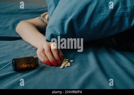 Eine junge Frau liegt auf dem Bett, ihr Kopf liegt unter dem Kissen. Stockfoto