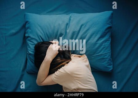 Eine Frau liegt mit Kopfschmerzen im Bett. Stockfoto