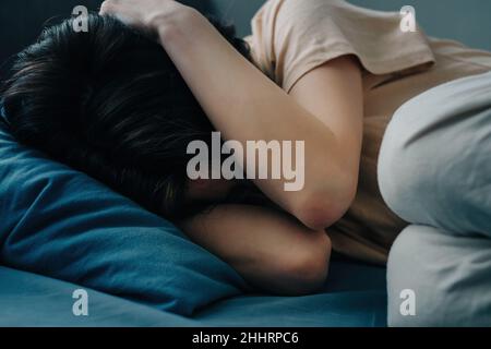 Die Frau im Bett umarmte ihren Kopf. Stockfoto
