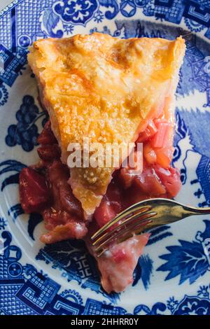 Erdbeer-Rhabarber-Kuchenscheibe auf blauem japanischem Teller Stockfoto