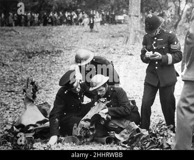 Ein Feuerwehrmann, der einem Polizisten, der sich nach einem Bombenangriff im Zweiten Weltkrieg V1 Notizen macht, die Formulierung über die Überreste einer Bombe vorliest. Ein Park im Süden Englands wurde getroffen und forderte einige Verletzte. 24th. Juli 1944. Stockfoto