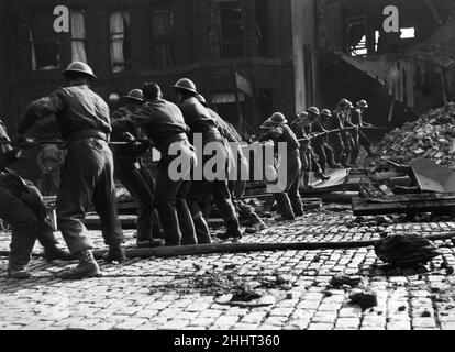 Soldaten des Manchester-Regiments von 8th in Ardwick Green arbeiten zusammen, um die Trümmer aus ihren Kasernen zu räumen und ihre gefangenen Kameraden nach einem deutschen Luftangriff freizulassen. Die Bilder zeigen eine Gruppe von Soldaten, die am Seil ziehen, um das Wrack zu räumen. 14th. März 1941. Stockfoto