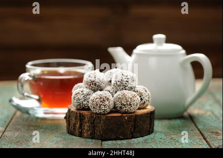 Hausgemachte vegane Süßigkeiten in Kokosnussspins serviert mit dampfendem schwarzen Tee-Copyspace Stockfoto