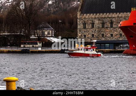 Das Rote Kreuz-SAR-Schiff Hordaland Røde Kors verlässt den Binnenhafen von Bergen, Norwegen. Vorbei an einem Offshore-Versorgungsschiff in Festningskaien und der Stockfoto