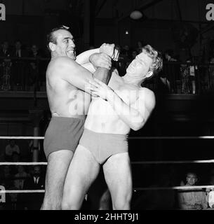 Primo Carnera, Schauspieler und professioneller Wrestler, ebenfalls ein ehemaliger Profi-Boxer, fotografierte Drehszenen für den neuen Film A Kid for Two Farthings in den Shepperton Studios, Surrey, England, 13th. September 1954. Das Set ist eine Darstellung eines Wrestling-Rings in East London. Er spielt Python Macklin, gegenüber Joe Robinson, dem World Wrestling Champion von 1951 und aktuellen Judo-Weltmeister, als Sam Heppner. Stockfoto