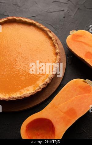 Kürbiskuchen mit geschnittenem Butternusskürbis auf dunklem Gips-Hintergrund von oben Stockfoto