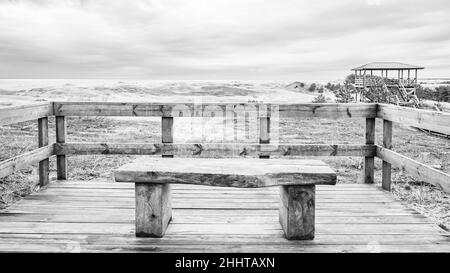 Eine Holzbank mit Blick auf die Sanddünen der Kurischen Lagune und der Kurischen Bucht Stockfoto