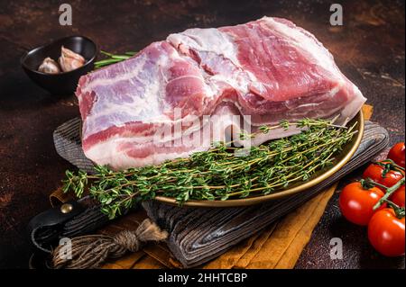 Farm frischen Schweinebauch, rohes Fleisch auf einem Teller mit Gewürzen. Dunkler Hintergrund. Draufsicht Stockfoto