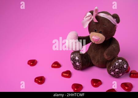 teddybär Teddybär hält ein flauschiges Herz in seinen Pfoten. Rosa Hintergrund. Stockfoto