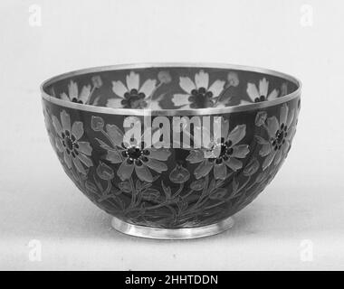 Bowl 1903 Fernand Thesmar Französisch in dieser plique à jour-Technik gibt es keine tragende Metallstruktur für diese Emaille. Der Stoff der Schale ist der Emaille selbst, der während des Brennens durch ein dünnes Blatt Gold, das später entfernt wird, an Ort und Stelle gehalten wird.Thesmar hat zwischen 1891 und 1903 viele kleine Schalen dieser Art ausgeführt. Alle sind von islamischem Stil inspiriert und beziehen diese Gruppe stärker auf das nahöstlich inspirierte Glas seines Zeitgenossen Philippe-Joseph Brocard (gestorben 1896) als auf seine eigene Arbeit in Cloisonné-Emaillen. Schüssel. Französisch, Neuilly-sur-seine, Paris. 1903. Plique à jour emailliert, Gold. Emaille Stockfoto