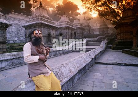 Sadhu (Heiliger Mann) sitzt neben einer Reihe von Shiva-Tempeln, Pashupatinath Hindu-Tempel, Pashupatinath, Nepal Stockfoto