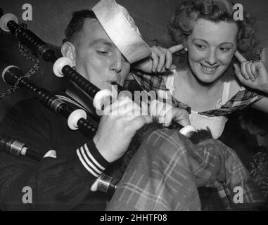 Eine amerikanische Seemannin Glasgow probiert zum ersten Mal die Dudelsäcke aus, während ein Mädchen ihre Finger in die Ohren legt, um den Lärm zu blockieren.10th. September 1952. Stockfoto