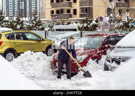 Krasnodar, Russland - Januar 24 2022: Senior man Removal Snow with a Shovel. Schaufelende Straße von verdecktem fallendem Schnee Stockfoto