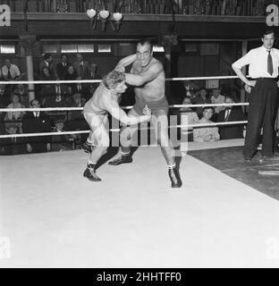 Primo Carnera, Schauspieler und professioneller Wrestler, ebenfalls ein ehemaliger Profi-Boxer, fotografierte Drehszenen für den neuen Film A Kid for Two Farthings in den Shepperton Studios, Surrey, England, 13th. September 1954. Das Set ist eine Darstellung eines Wrestling-Rings in East London. Er spielt Python Macklin, gegenüber Joe Robinson, dem World Wrestling Champion von 1951 und aktuellen Judo-Weltmeister, als Sam Heppner. Stockfoto