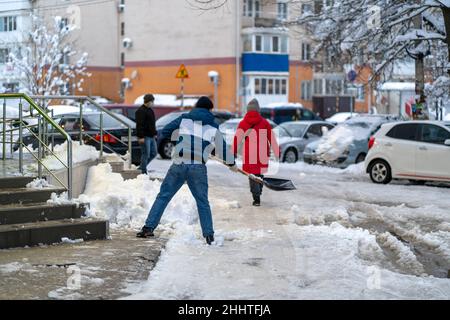 Krasnodar, Russland - Januar 24 2022: Man Removal Snow with a Shovel. Schaufelende Straße von verdecktem fallendem Schnee Stockfoto