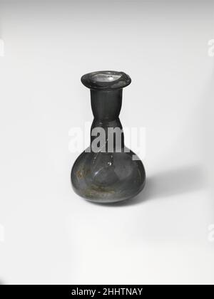 Parfümflasche aus Glas 1st. Jahrhundert n. Chr. Römische kleine Flasche.Durchscheinendes rauchgrau.schräge Kante, ausgeklappt, über und in, mit erhobener Innenlippe auf einer Seite; zylindrischer Hals, nach unten verjüngend, horizontal an der Basis eingehiftet; hohe Schulter mit konvexer Seite, an der Basis durch eine andere horizontale, verschraubte Einrückung markiert; Hocke Knollenkörper, dann steil bis klein abfallend, flach bottom.Complete, aber am Körper und über den Boden stark gesprungen; wenige Blasen und Blasstreifen; kleine Flecken von Abstumpfungen und Verwitterung auf der Außenseite, einige Bodenverkrustungen und weißliche Verwitterung auf der Innenseite. Parfümbot aus Glas Stockfoto