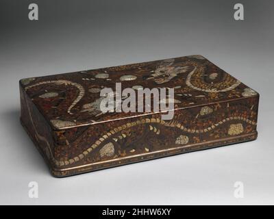 Kleiderbox mit Drachen verziert 19th Century Korea Diese Box ist ein lebendiges Design mit zwei Drachen, die ein flammendes Juwel jagen. Die langen, sinewigen Körper der Tiere umhüllen die Seiten der Schachtel; ihre Köpfe stehen sich an den gegenüberliegenden Ecken oben gegenüber. Die meisterhafte Mischung aus verschiedenen Materialien – Perlmutt, Schildpatt und ray Skin – hebt unterschiedliche Texturen hervor und betont nicht nur die taktile Qualität der mythischen Tiere, sondern auch ihren dynamischen Charakter. Kleiderbox mit Drachen verziert 40528 Stockfoto